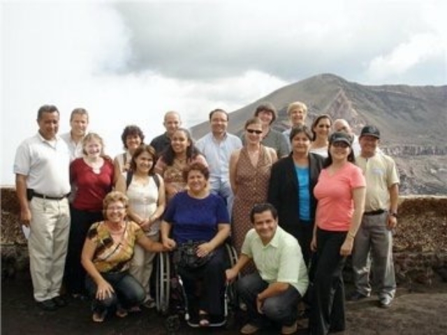 Rhonda with a large group of people with and without disabilities in front of a volcano in Nicaragua.
