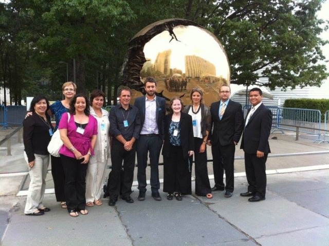 10 colleagues from around the world in front of a reflective globe by the United Nations.