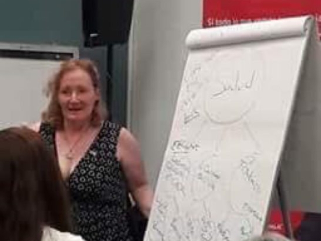 Rhonda standing at a white board while facilitating an exercise in a training of women with disabiltiies