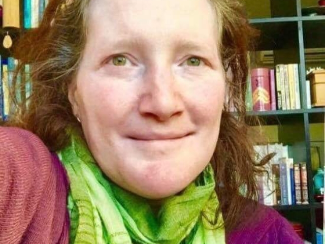 Rhonda smiling at camera with books in the background.