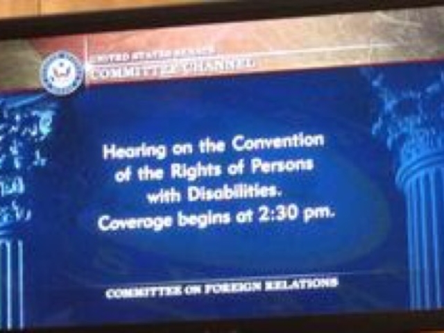 Image of a television screen in the Senate that says "Hearing on the Convention of the Rights of Persons with Disabilities. Coverage begins at 2:30 pm. Committee on Foreign Relations."