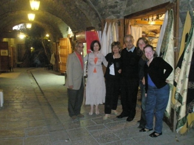 Rhonda with 5 other colleagues in an old market with cobblestone and arches, in front of a store with fabrics, following a meeting.
