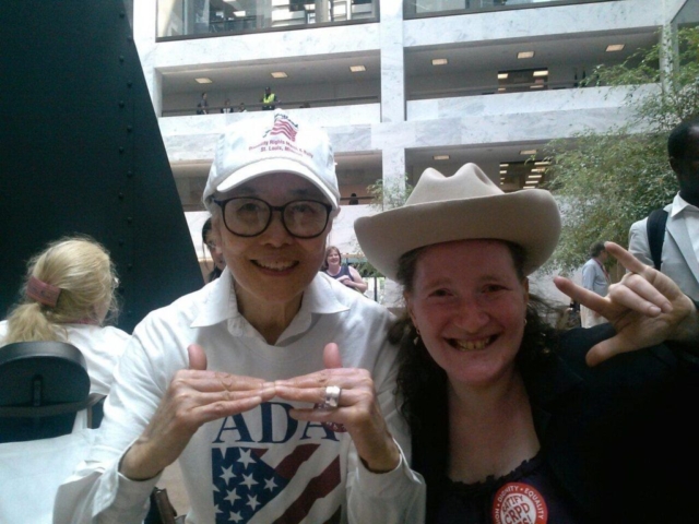 Yoshiko signing 'Justice'; Rhonda signing 'I love you' and wearing the hat of Justice Dart.