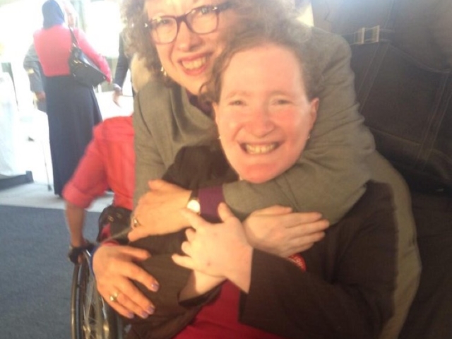 Sweet moment of 2 colleagues smiling at the camera at an event