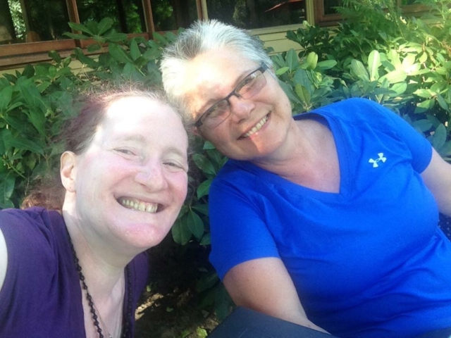 Two colleagues smilng at the camera, heads together.