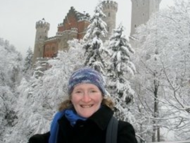 Rhonda in front of Neuschwanstein Castle in Germany and snowy trees.