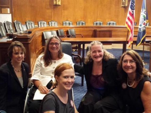 CRPD grassroots leadership in the Senate chamber following press conference. US and Senate flags in the background.