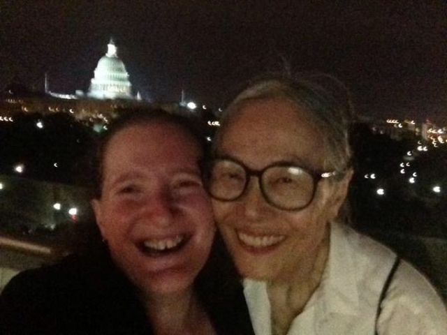 Yoshiko Dart and Rhonda smiling with a nighttime view of the U.S. Capitol.