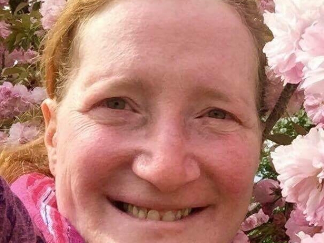 Rhonda in front of pink cherry blossoms.