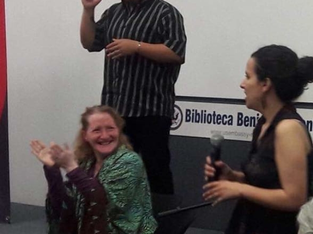 Rhonda clapping and laughing at Mexico City training. Sign language interpreter behind her.