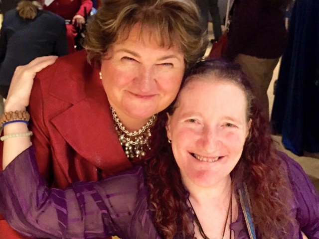 Two smiling women wearing reds and purples at the USICD gala for Dec. 3.