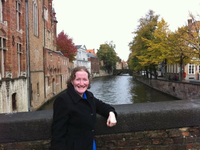 Rhonda on a bridge over a river in Belgium, older buildings and trees line the water