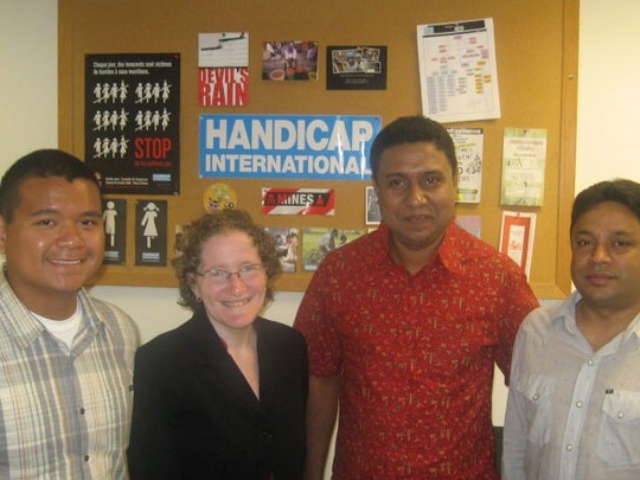 Rhonda with colleague and 2 international visitors in front of a bulletin board at HI, 2009.