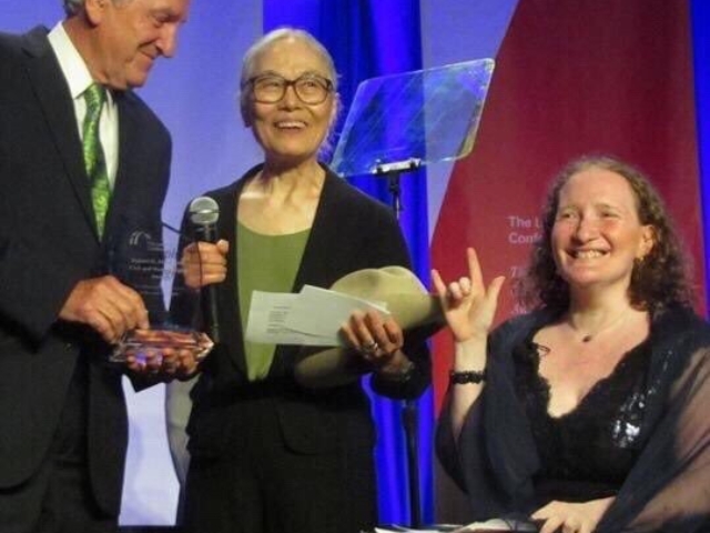 Rhonda giving an ASL "I love you" - sitting in a wheelchair - with Senator Harkin and Yoshiko Dart, LCCHR Gala, 2014