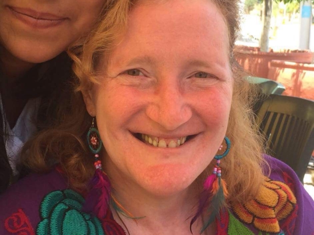 Rhonda wearing a purple mexican shirt, smiling.