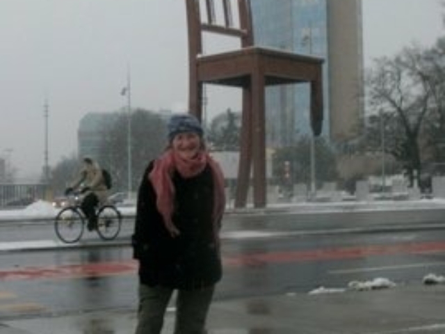 Rhonda stanidng before a large statue of a chair with one leg.