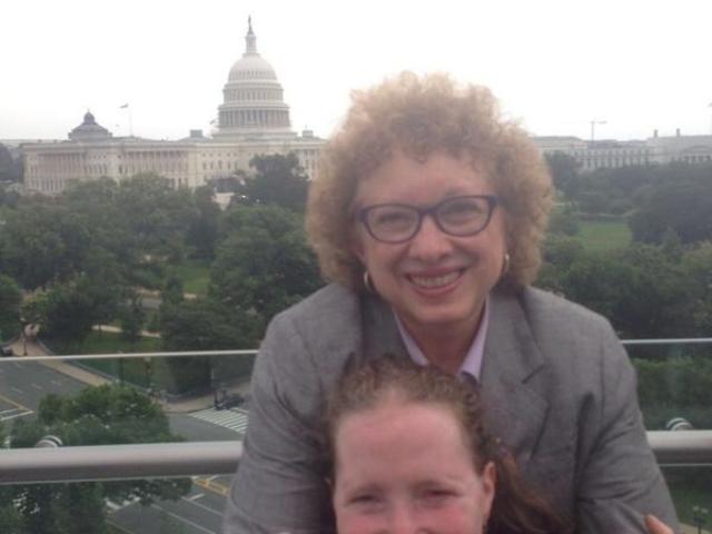 Rhonda being embraced from behind from Joyce Bender, in front of the U.S. Capitol. Both grinning.